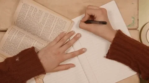 A woman's hands writing down an essay.
