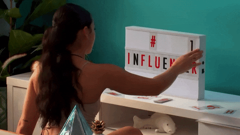 A young woman adding the text '#1 influencer' to a sign board in her bedroom