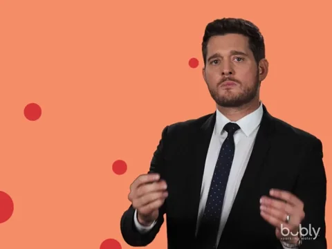 Michael Buble, dressed in a black suit, pointings and says, 