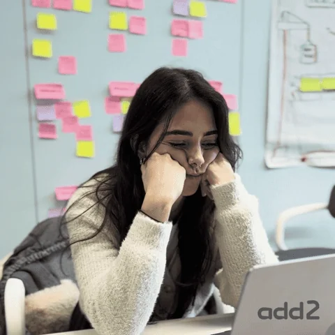A woman bows her head in frustration at her desk.
