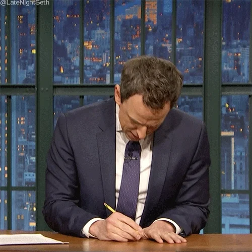 Seth Meyers writing with a pencil frantically and with a confused expression