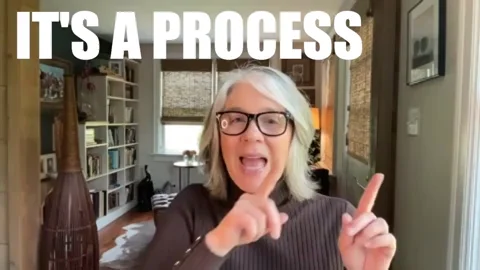 A woman points her fingers from one side of her body to the other. She says, "It's a process."