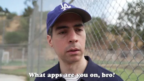 GIF: Person in baseball diamond with a blue LA baseball cap and navy blue polo shirt on, asks, 'What apps are you on, bro?'