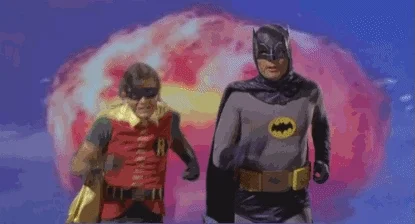 Batman and Robin running away from a mushroom cloud.