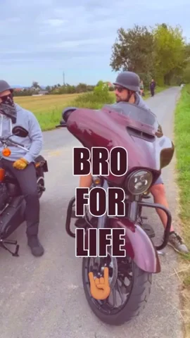 Two men riding a motorcycle bump fists with the quote “Bro for life.”