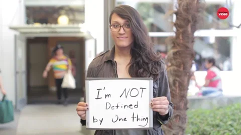 A person holds sign saying 'I'm NOT defined by one thing'.