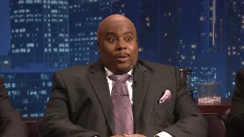 A man in a suit brings his hands together while smiling slightly, with on-screen text that reads “I’m listening.”