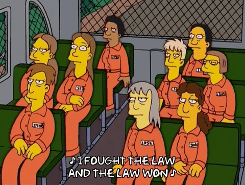 A group of Simpsons characters on a prison bus. They sing, 