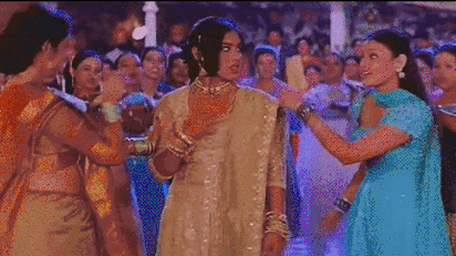 A Bollywood dance scene: two women push another, but then start to follow her dance moves