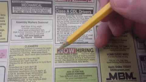 Person circling a job ad in a newspaper with a pencil.