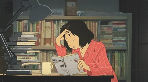 A tired student reading at her desk until her head falls onto the open book.