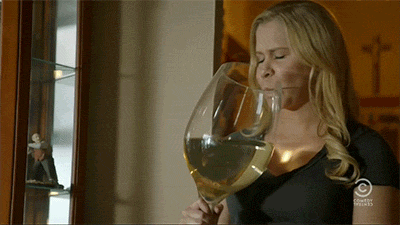 A woman drinking a comically oversized glass of wine.