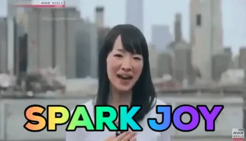 Marie Kondo making her signature move of kicking up a heel and pointing skywards with rainbow letter caption, 'Spark Joy.'