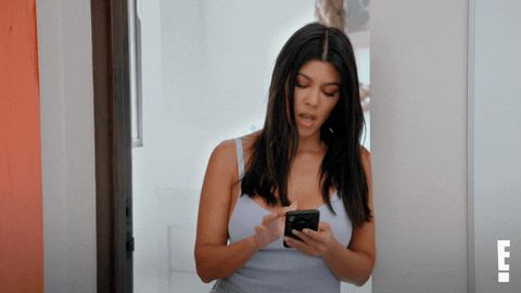 Kourtney Kardashian looks down on her phone, blows raspberries and says 