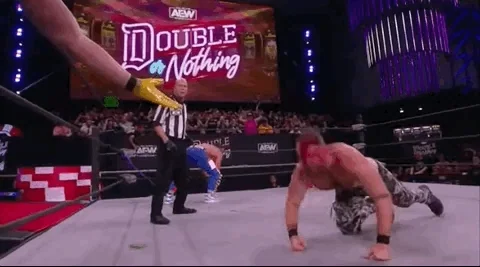 A professional wrestler crawls over to the ring edge and tags his team mate into the fight.