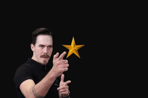 A man pointing playfully as stars pop out of his fingers.