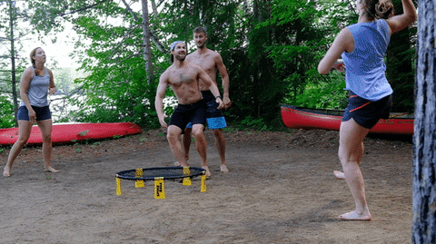 Four players playing Spikeball at a campground.