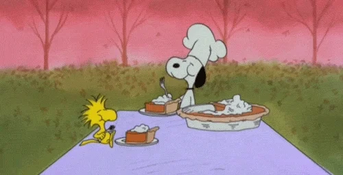 Cartoon characters from Charlie Brown at a picnic, happily eating a large pie. 