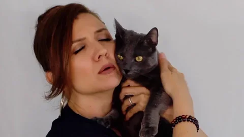 A woman holding cat closely and crying while petting it.