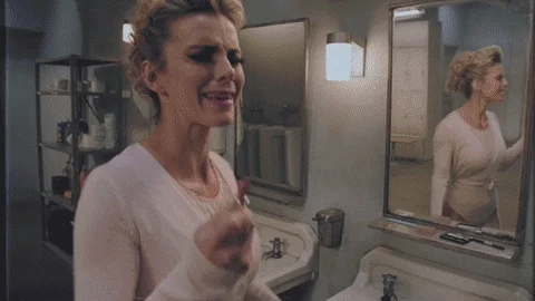 A woman looking in the mirror, applying lipstick, and transforming into her wrestler persona.