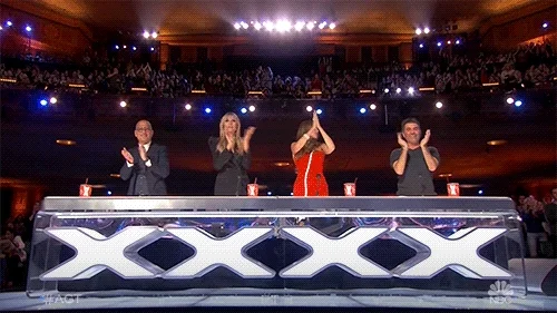 A four-person judge panel giving a standing ovation.