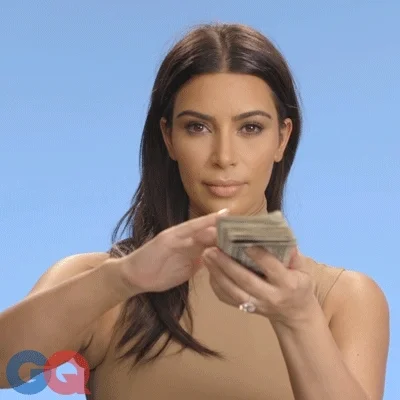Kim Kardashian playing with a stack of money.