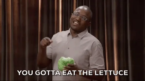Hannibal Buress holding a lettuce on stage. He says, 