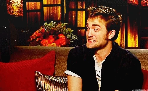 Robert Pattinson sitting on couch with a surprised and nervous facial expression.