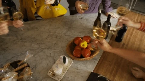People at a table bringing their wine glasses together with cheers.