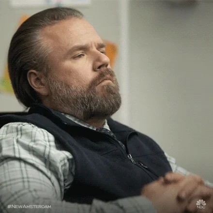 A character from New Amsterdam putting his hands to face and thinking.