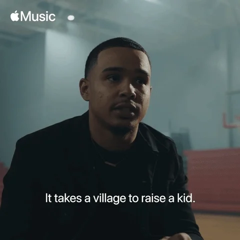 Man singing with a spinning background with overlaid text that reads 'it takes a village to raise a kid.'