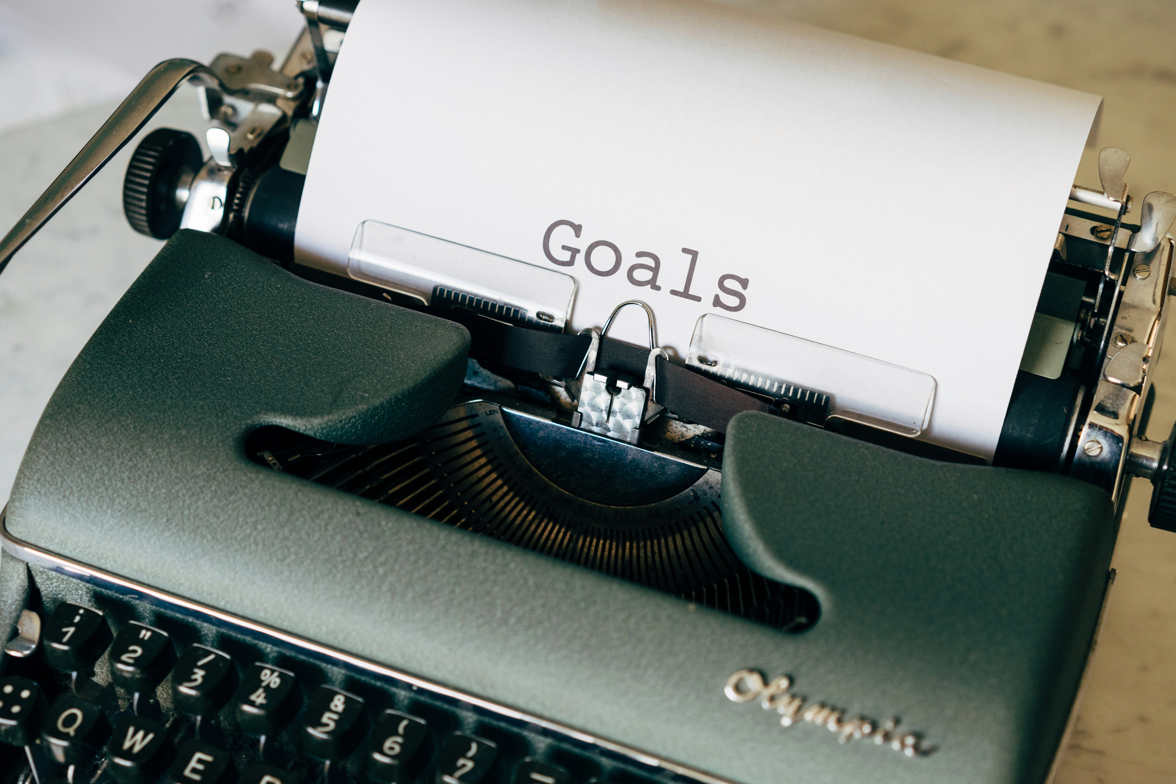 An image of a green typewriter with a paper with the word 'goals' typed out