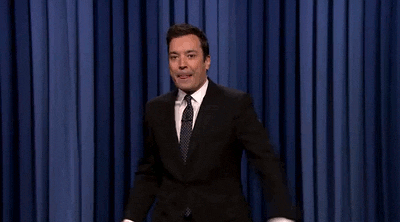Actor Jimmy Fallon is excitedly punching with his right fist up in the air