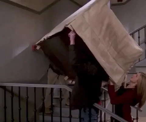 Three characters from the show Friends push a couch up the stairs of an apartment building.
