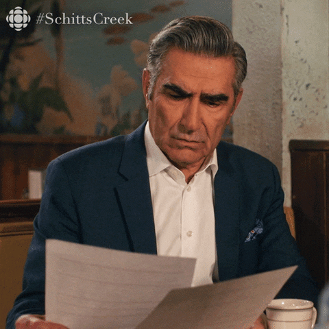 The dad from Schitt's Creek looking at a menu in a restaurant. He asks, 