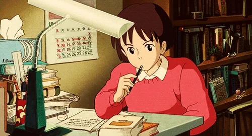 Character from Studio Ghilbi's 'Whisper of the Heart' doing work at a desk.
