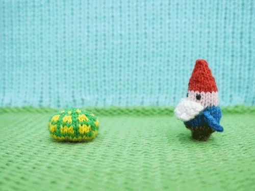 GIF shows knitted figurines, a turtle & garden gnome. The gnome taps the turtle on its shell, and the turtle comes out. 