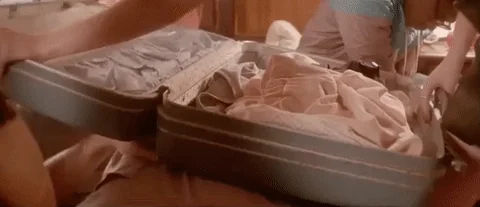 Someone closing a packed suitcase.