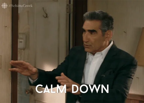 An older man holding his hands up gently to calm someone down, saying, "Calm down, breathe."