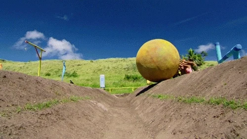 GIF of a team of people trying to push a large boulder over a hill