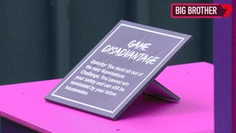 A big brother contestant picks up a cube from a podium to reveal a card that says 