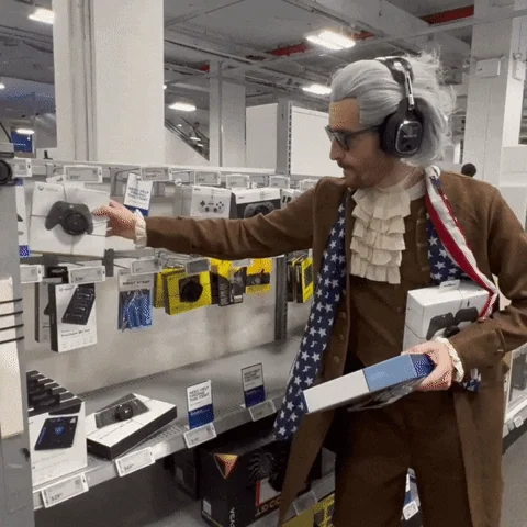 A man dressed up as an American Founding Father buys a video game controller. 
