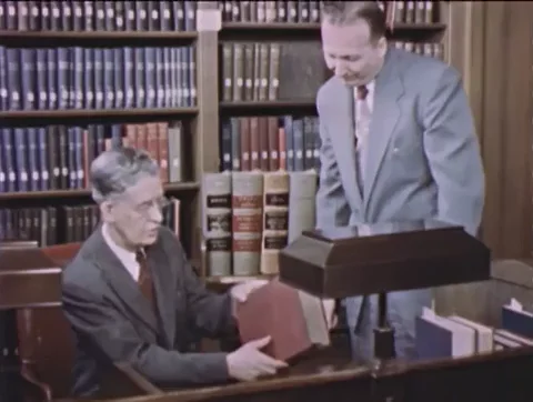 Old footage of US policymakers looking through policy books.