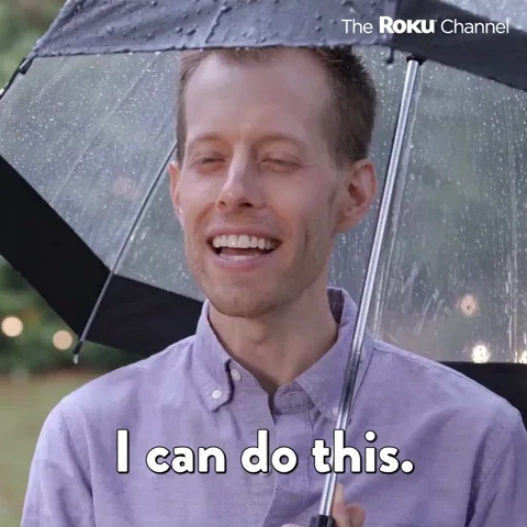 A man under an umbrella in the rain smiles and says, "I can do this."