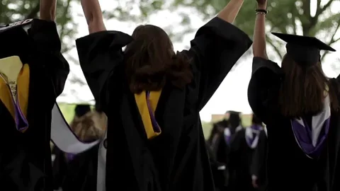 A student on graduation day running with hands up holding their cap.