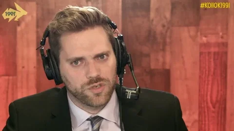 A man in a suit wearing a head set saying, "You tricked me?"