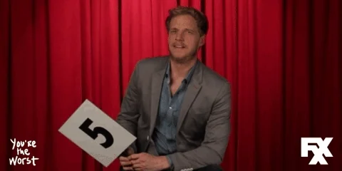 A person on a stage holding the number five on a sign.