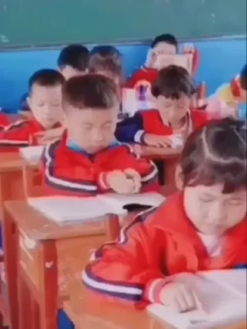 A little boy using both hands to pour imaginary information into his head from book.