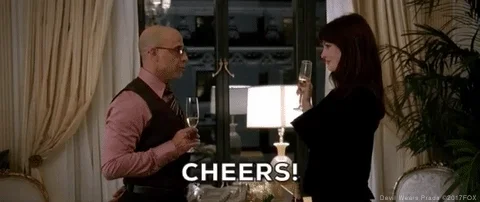 Anne Hathaway and Stanley Tucci clink champagne glasses.