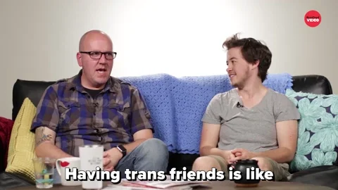 Two men sit on a couch. One says, 'Having trans friends is like having friends.'